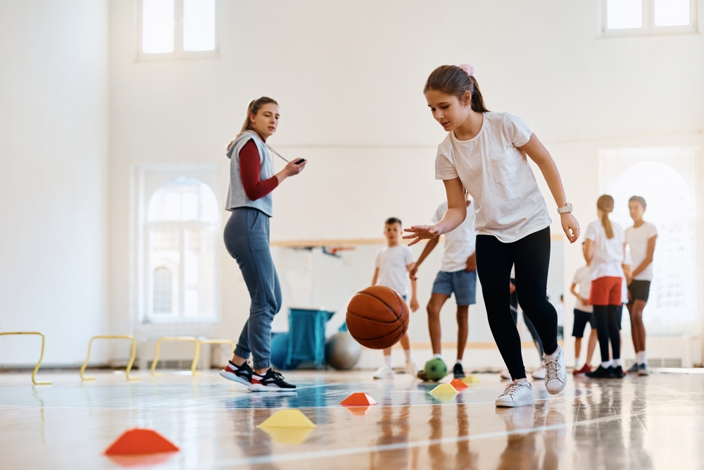 Elementary,student,leading,a,basketball,during,physical,activity,class,at